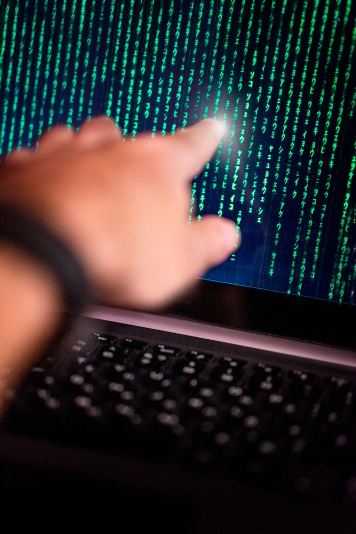 gallery-2 A person points at a glowing code on a computer screen, symbolizing technology interaction.